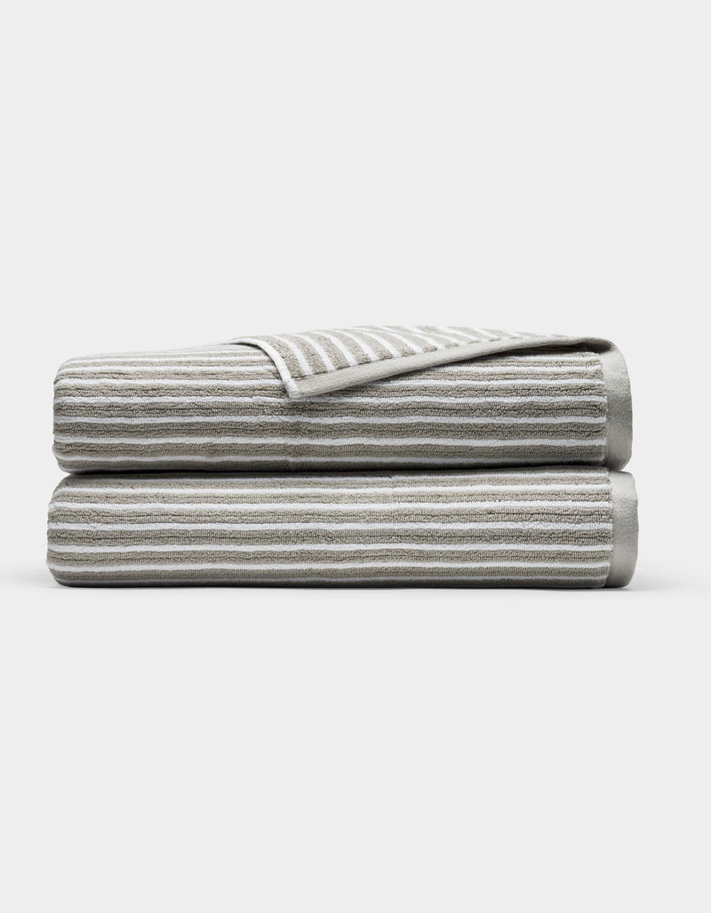 Two Cozy Earth Ribbed Terry Bath Sheets in gray and white stripes are folded and stacked on each other against a plain white background.