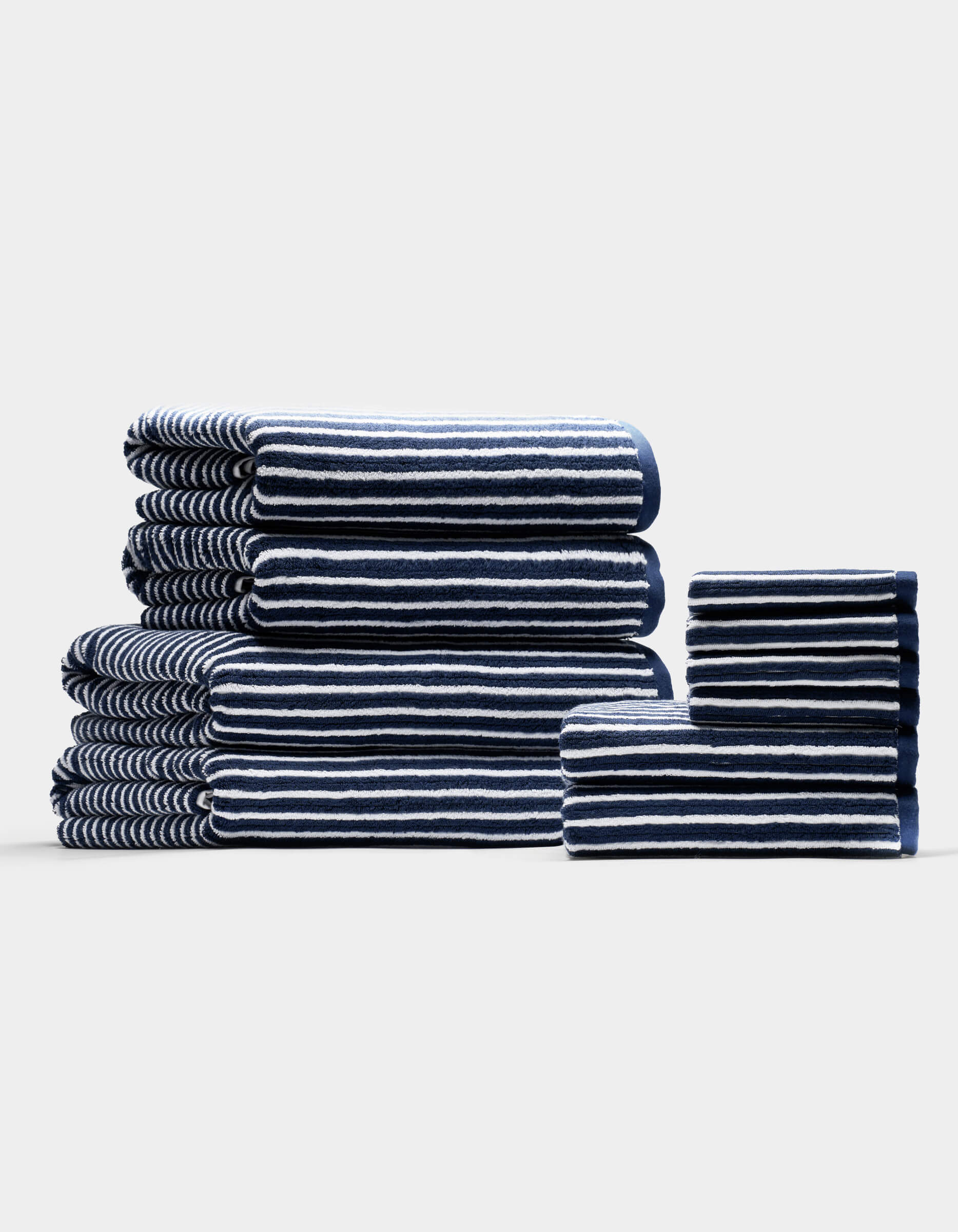 The Complete Ribbed Terry Bath Bundle by Cozy Earth features navy blue towels with white stripes, arranged by size on a plain, light background.|Color:Obsidian Stripe