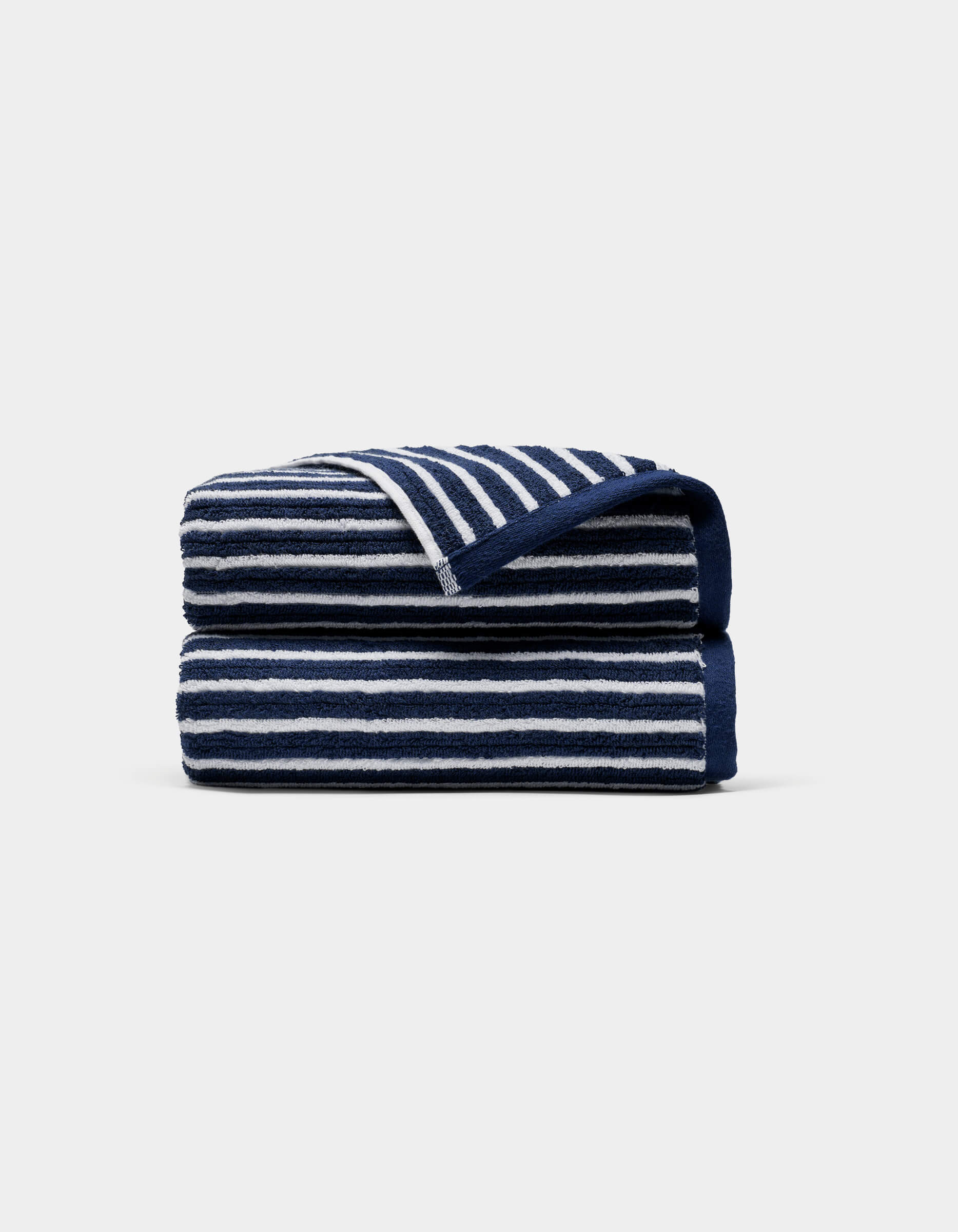 A Ribbed Terry Hand Towel by Cozy Earth, featuring horizontal navy blue and white stripes, is neatly folded against a plain light gray background.|Color:Obsidian Stripe