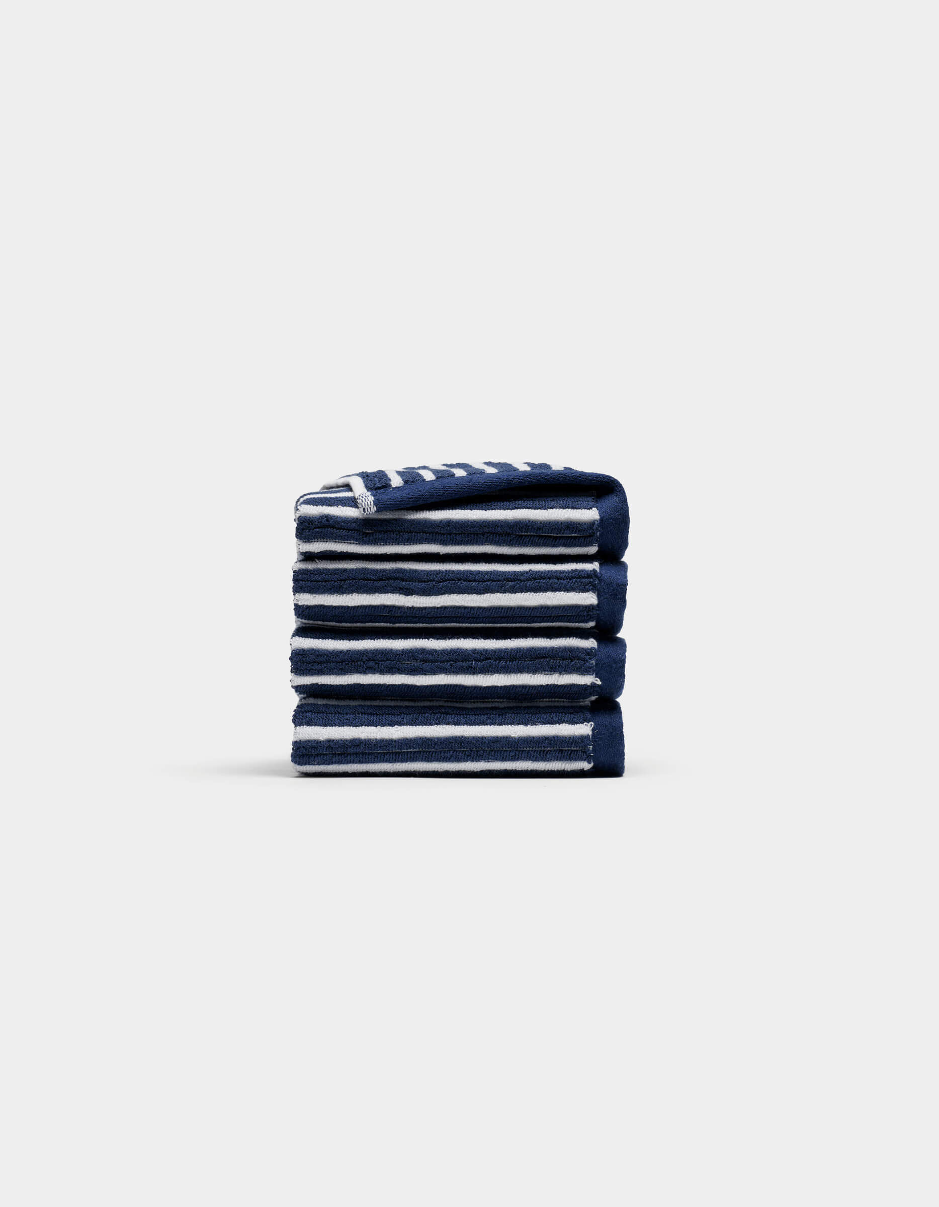 A neatly folded stack of four Cozy Earth Ribbed Terry Washcloths in navy blue and white stripes is centered on a plain, light gray background.|Color:Obsidian Stripe