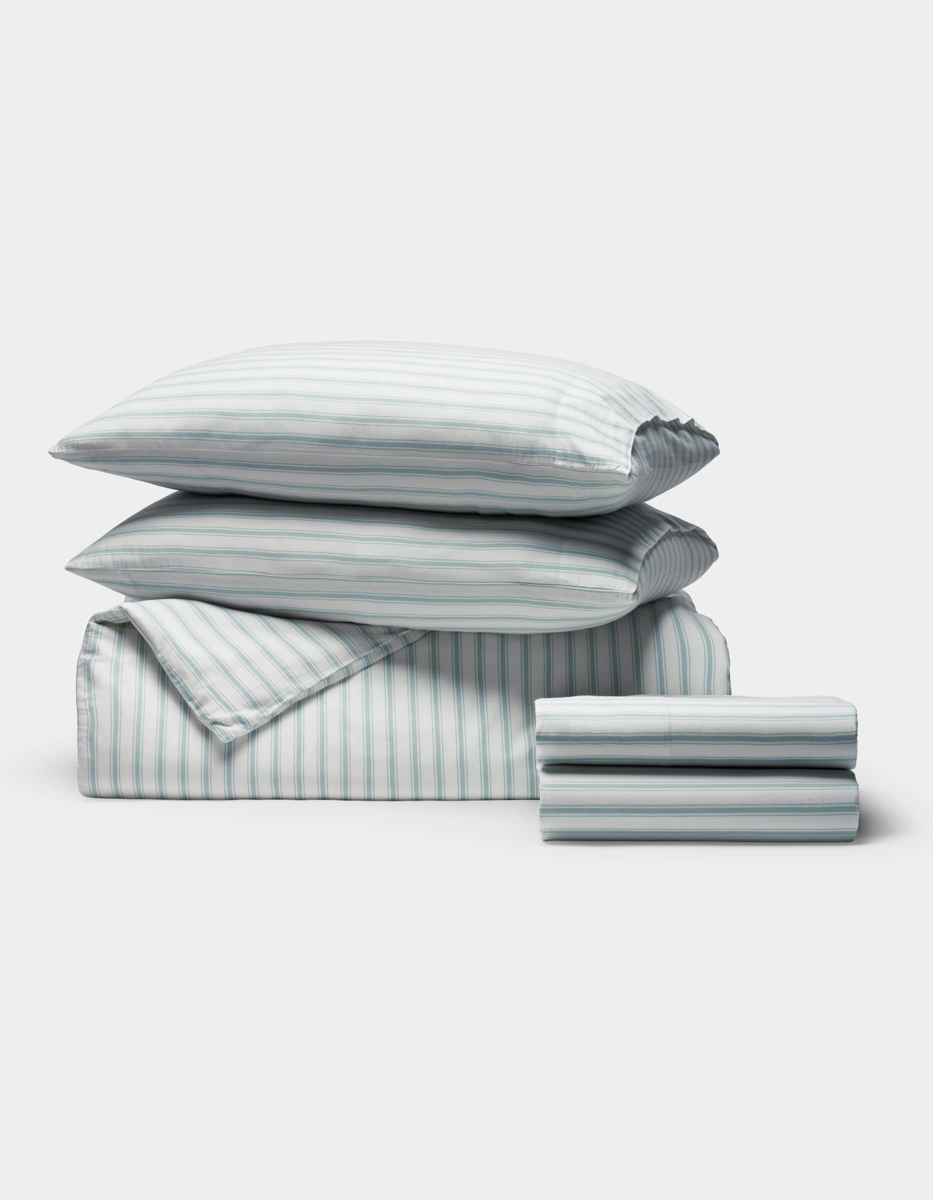 The Cozy Earth Soft-Wash Cotton Bedding Deluxe Bundle includes two pillows, a comforter, and sheets, all neatly folded with a light blue and white vertical stripe pattern.|Color:River and Sea Salt Stripe