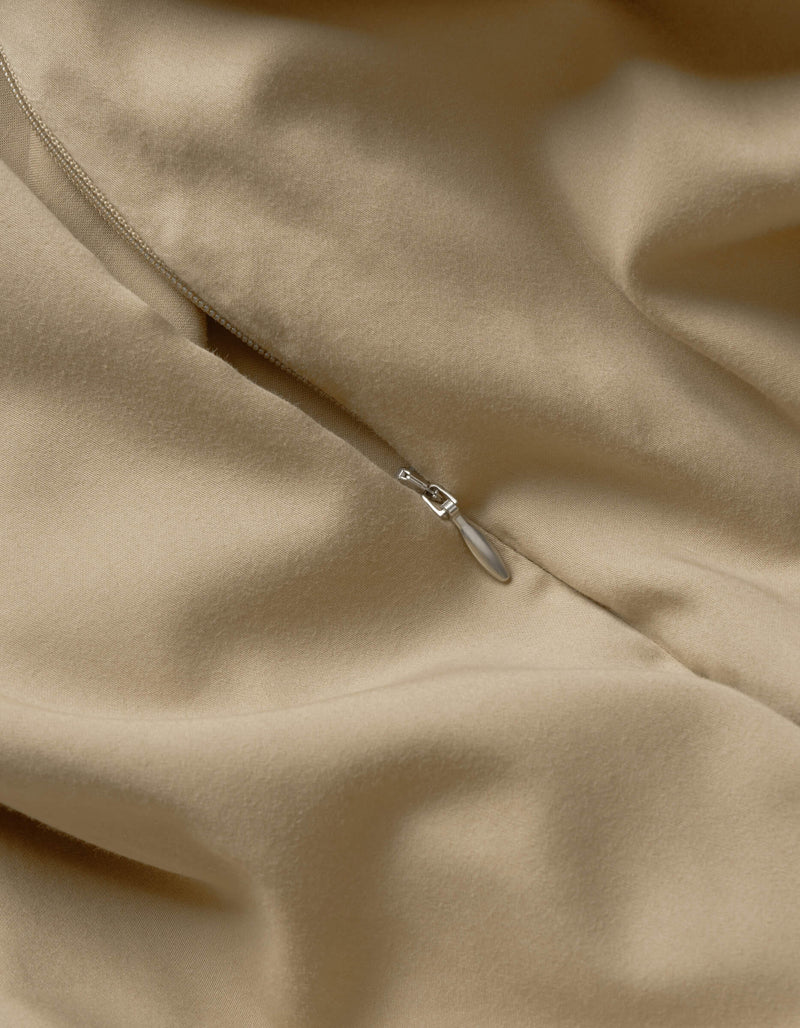 Close-up of Cozy Earth’s Soft-Wash Cotton Duvet Cover in beige, highlighting its smooth texture, soft folds, and a partially closed silver zipper.