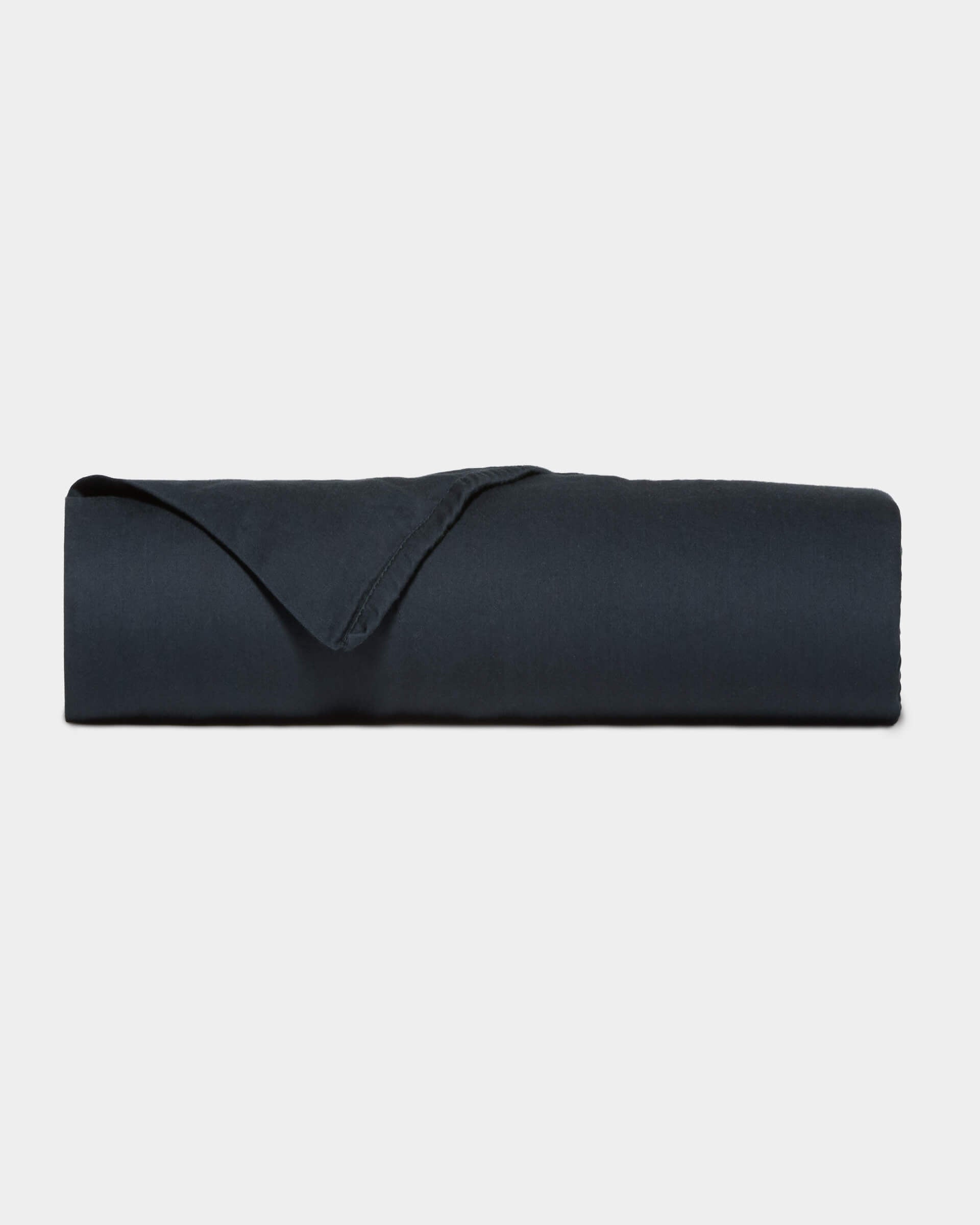 A neatly folded Soft-Wash Cotton Flat Sheet by Cozy Earth in dark navy blue is displayed against a plain light gray background.|Color:Eclipse
