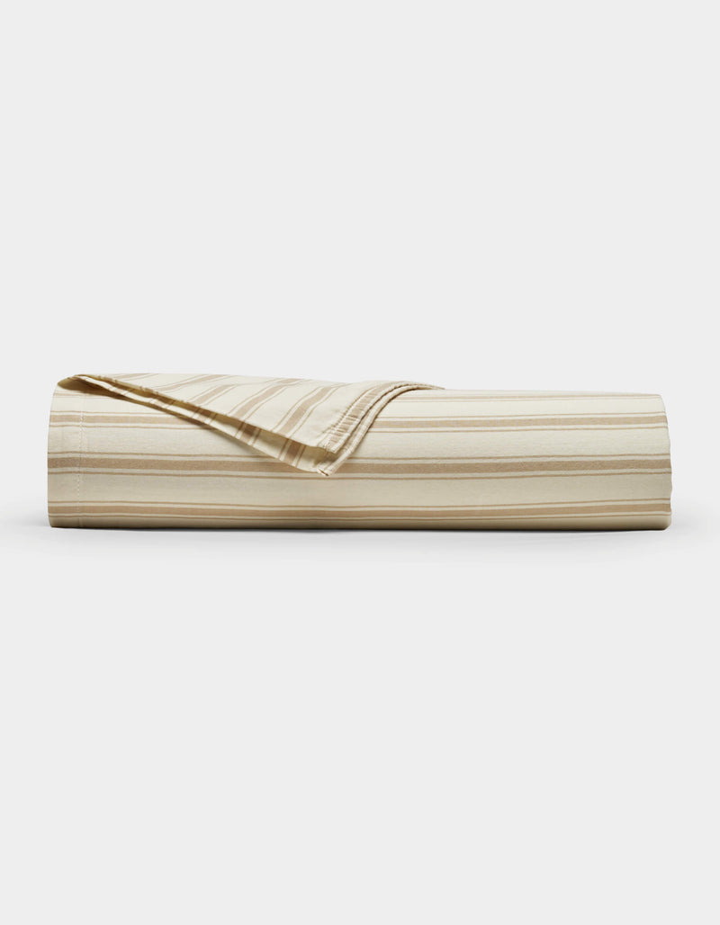 The Cozy Earth Soft-Wash Cotton Sheet Set, shown in beige and cream stripes, is neatly rolled with one corner folded back, displayed against a plain white background.