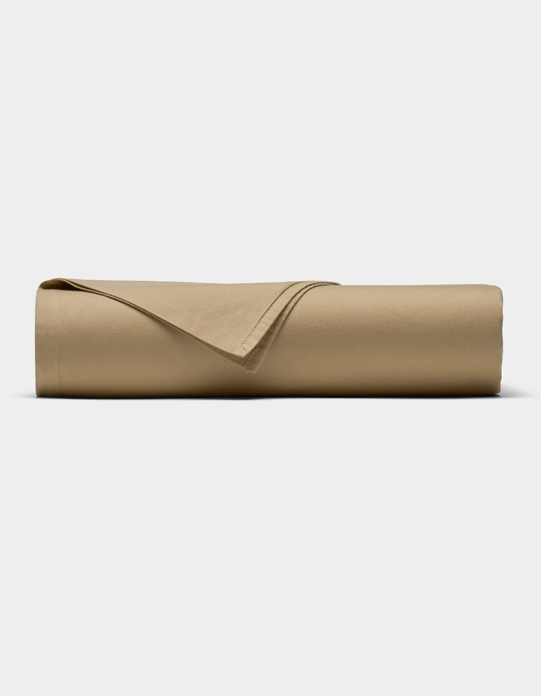 The Soft-Wash Cotton Sheet Set by Cozy Earth in tan is neatly rolled into a cylinder, with one corner folded back, displayed against a plain white background.|Color:Sandalwood