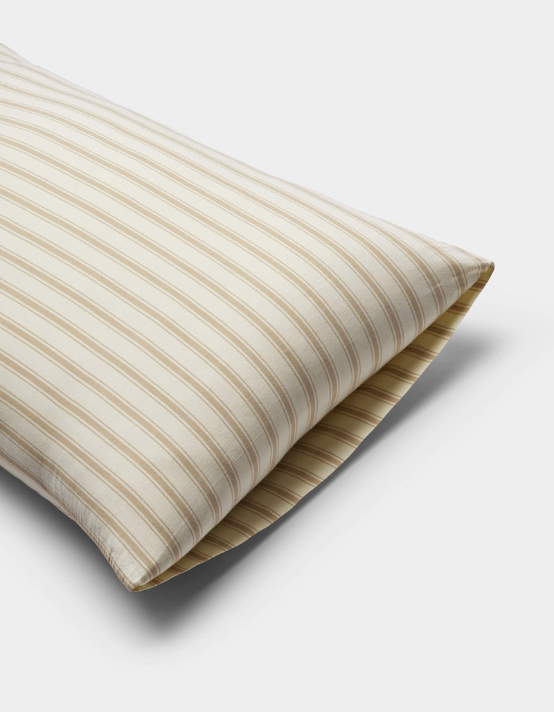 The Cozy Earth Soft-Wash Cotton Pillowcases in beige and white stripes are displayed on a plain white background, partially angled to highlight their soft texture and classic design.