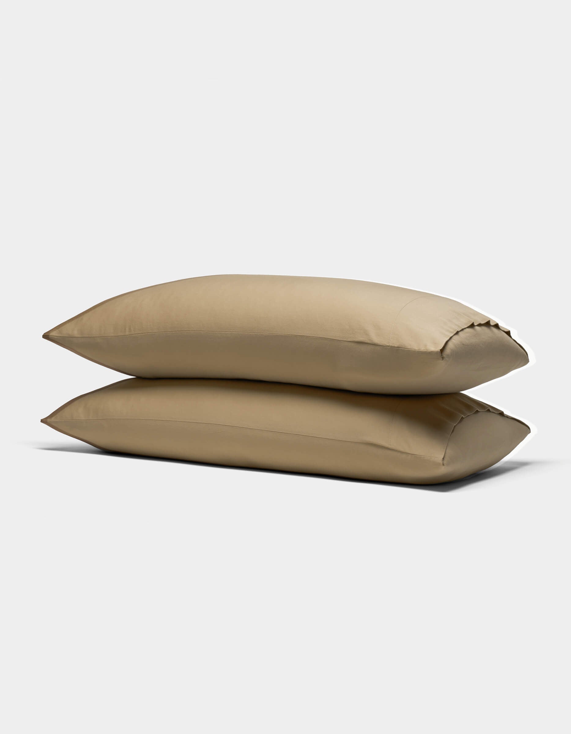 Two Cozy Earth Soft-Wash Cotton Pillowcases in light brown are stacked against a plain white background, showcasing their smooth texture and plush, comfortable appearance.|Color:Sandalwood