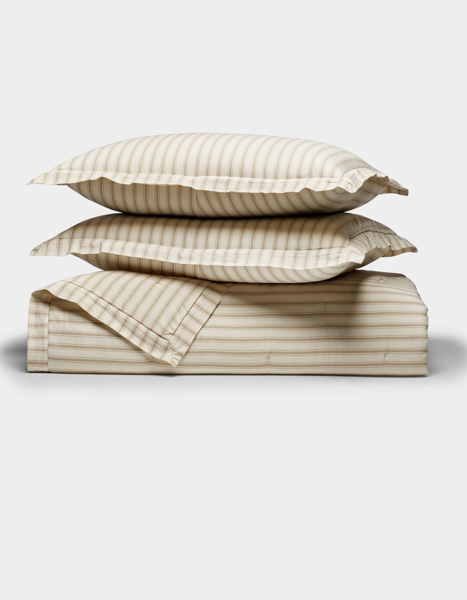 Two beige and cream striped Soft-Wash Cotton Quilt Set pillows by Cozy Earth are stacked on a matching folded sheet, displayed against a plain white background.|Color:Coconut and Sandalwood Stripe