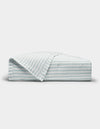 The Cozy Earth Soft-Wash Cotton Quilt is shown neatly folded with one corner turned back, revealing its light color and thin horizontal blue and gray stripes against a plain white background.|Color:River and Sea Salt Stripe