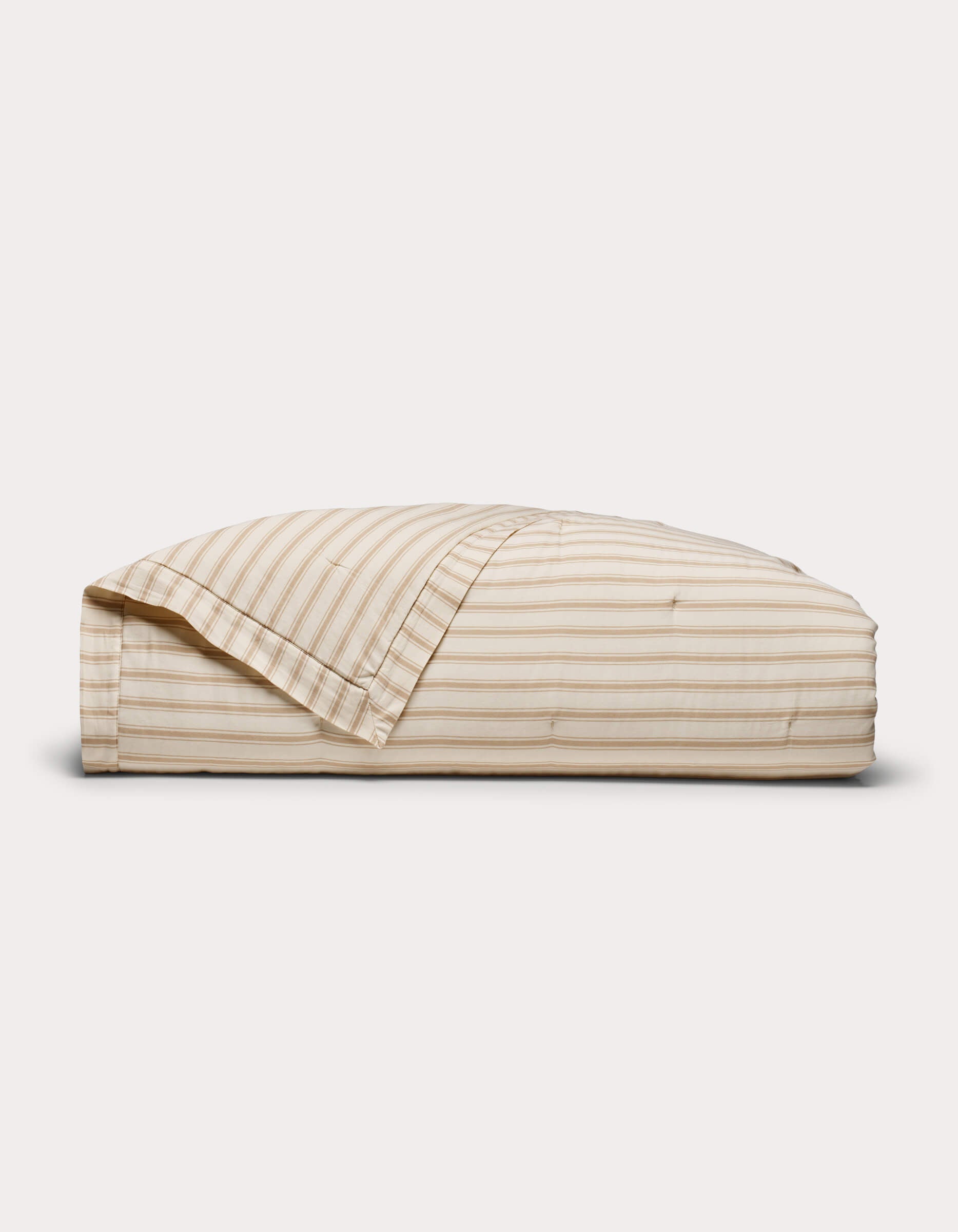 The Cozy Earth Soft-Wash Cotton Quilt, in beige and white stripes, comes neatly folded with a matching pillowcase set against a plain white background.|Color:Coconut and Sandalwood Stripe