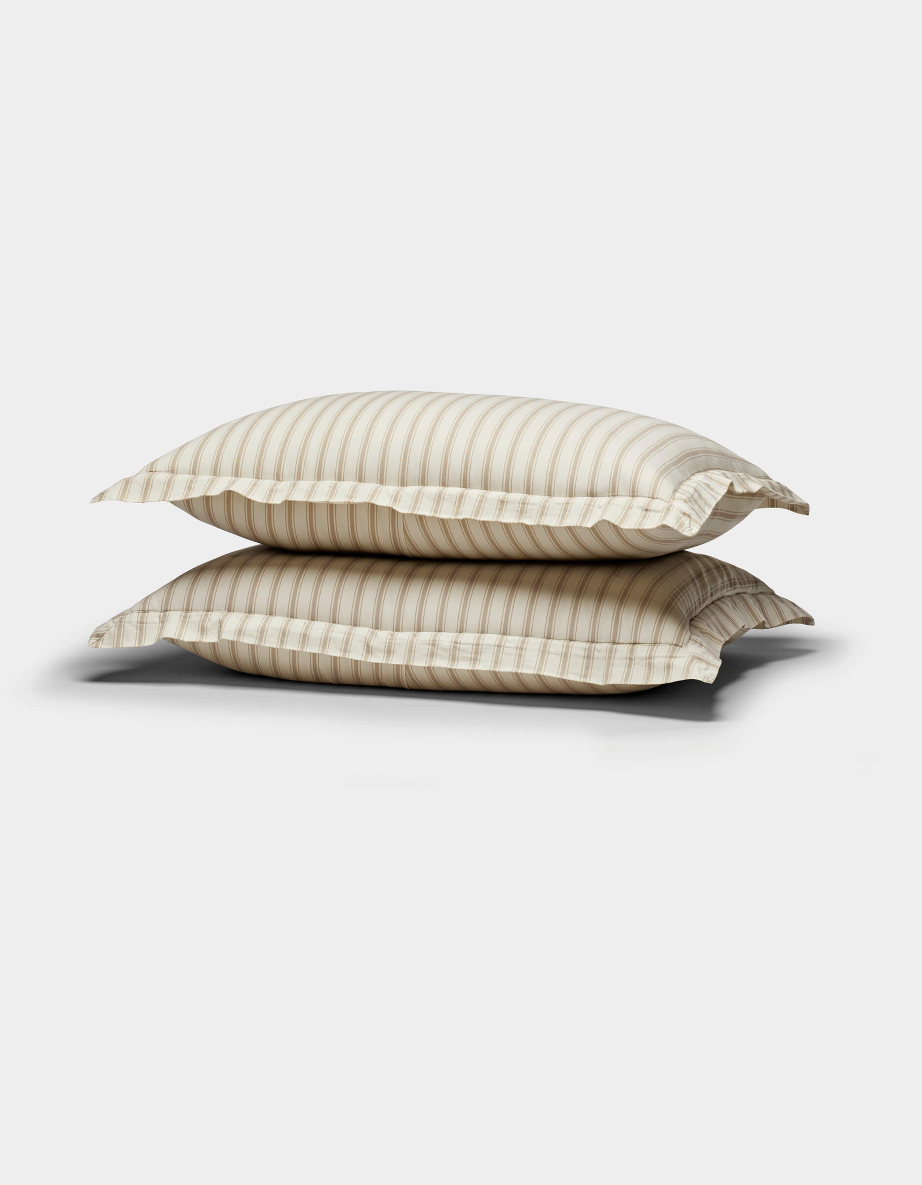 Two Soft-Wash Cotton Quilted Shams by Cozy Earth, in beige and white stripes, are stacked against a plain white background.|Color:Coconut and Sandalwood Stripe