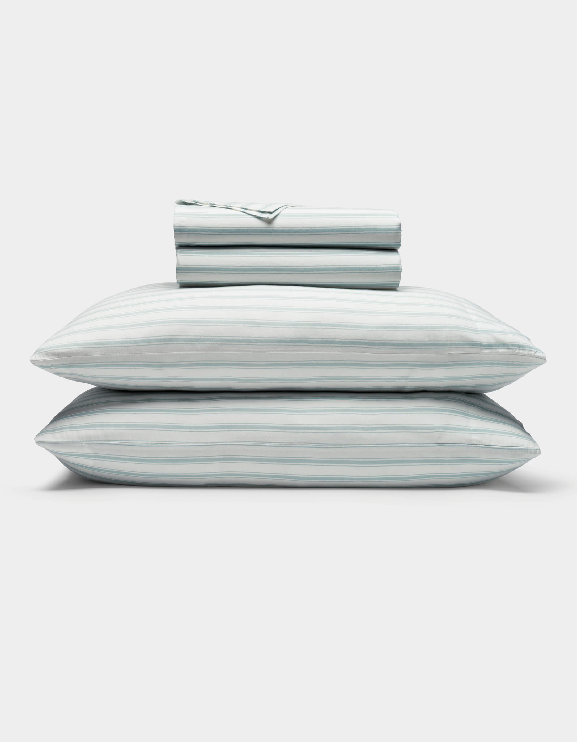 A neatly folded Soft-Wash Cotton Sheet Set by Cozy Earth in light blue and white stripes, featuring two stacked pillows and a folded fitted sheet, displayed on a plain white background.|Color:River and Sea Salt Stripe