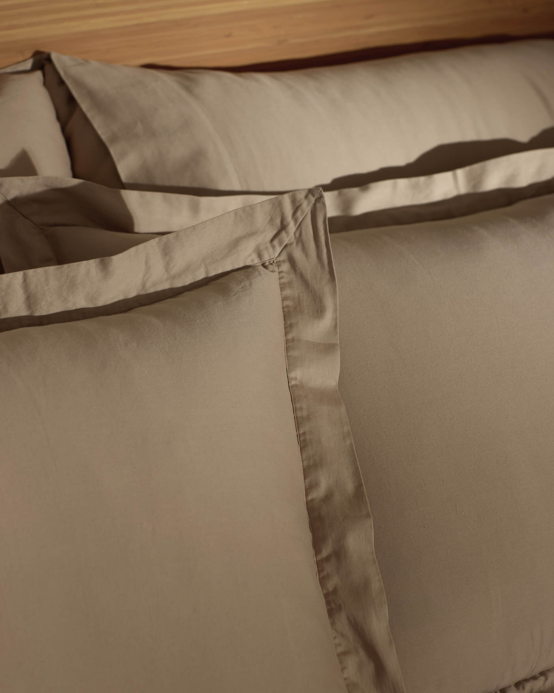 Close-up of Cozy Earth Soft-Wash Cotton Shams neatly arranged on a bed, highlighting their smooth texture, crisp edges, and subtle sheen.