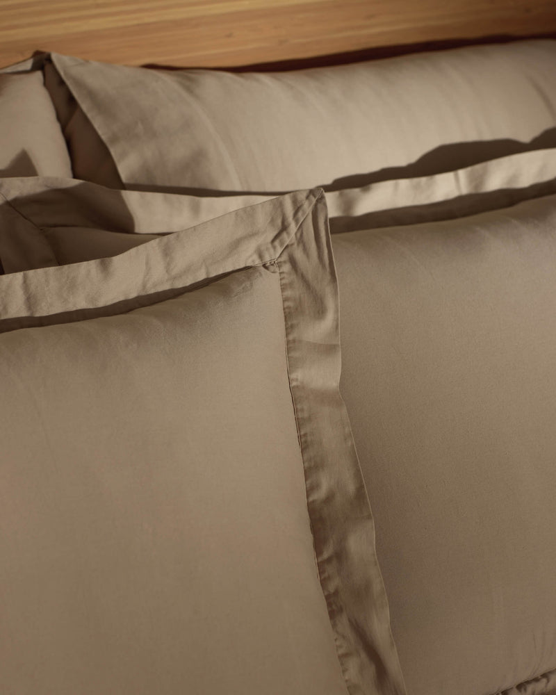 Close-up of Cozy Earth Soft-Wash Cotton Shams neatly arranged on a bed, highlighting their smooth texture, crisp edges, and subtle sheen.