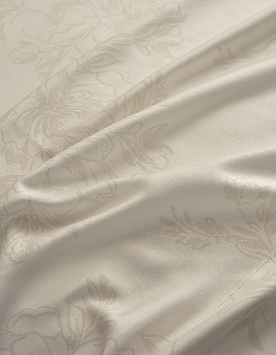 Close-up of a cream-colored satin fabric with a subtle, tonal damask floral pattern and soft folds. |Color:Sonoma Floral in Vintage White
