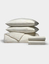 A Cozy Earth Bamboo Bedding Deluxe Bundle in cream, featuring a subtle floral pattern, with two pillows stacked atop a folded duvet and neatly folded sheets, displayed on a plain white background.|Color:Sonoma Floral in Vintage White