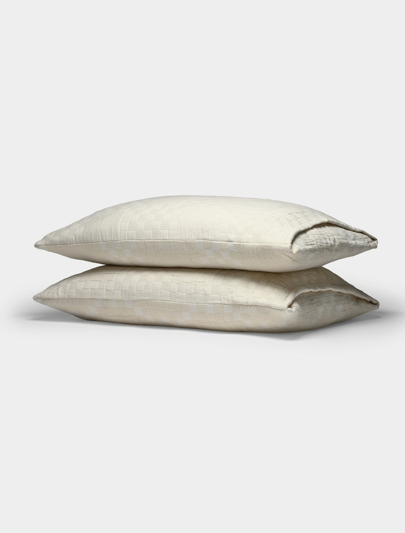 Two Sonoma Stitch Shams by Cozy Earth, featuring a subtle checkered pattern in a cream color, are stacked atop each other against a plain white background.