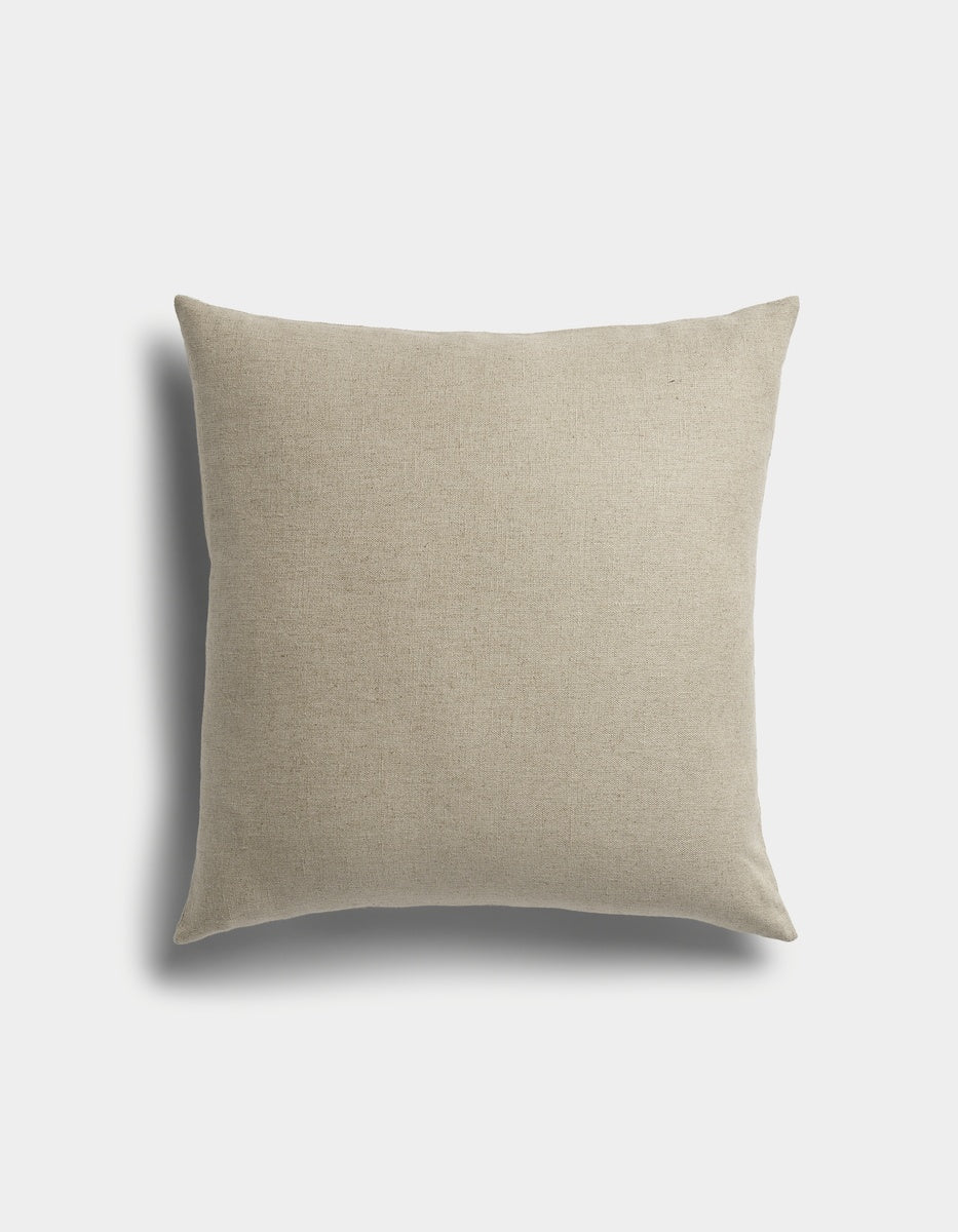 The Sonoma Throw Pillow by Cozy Earth is a square beige cushion with a plain fabric cover, displayed against a white background featuring a faint shadow on the left side.|Color:Tallow|Size:24" x 24"