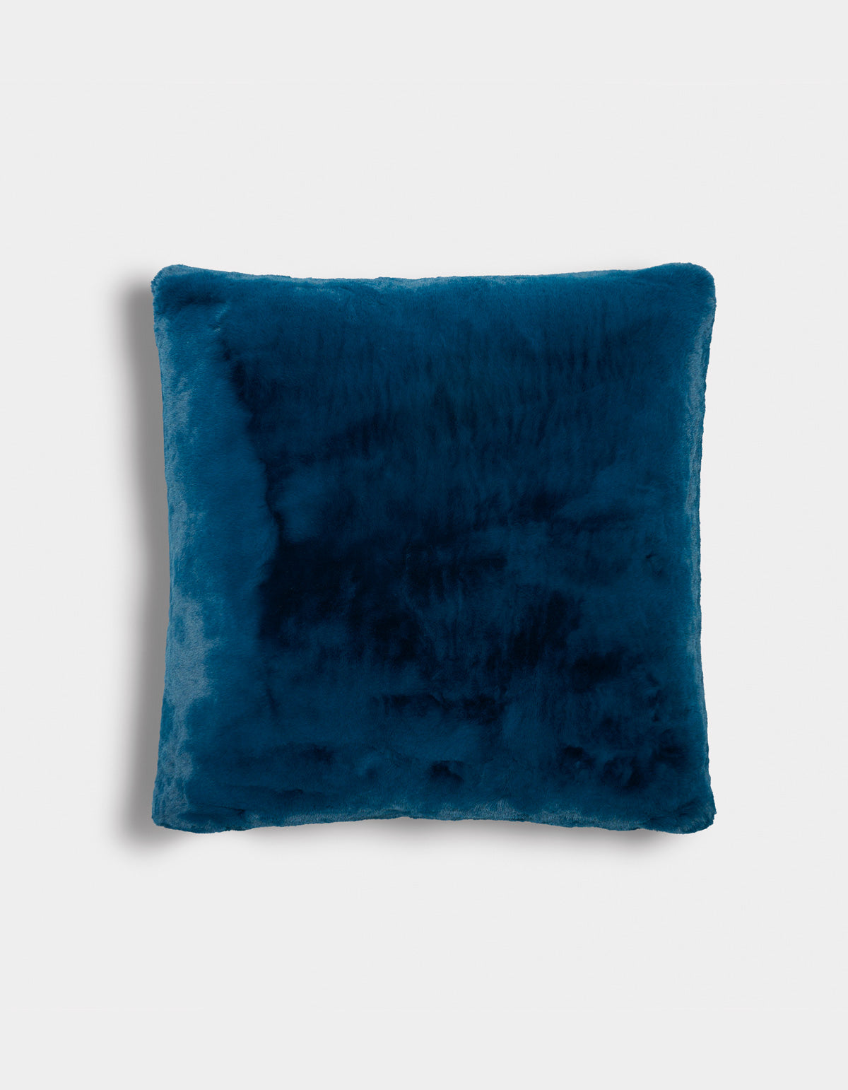 The Superplush Cuddle Pillow by Cozy Earth, featuring a square shape and deep blue faux fur, is displayed against a plain white background. Its soft and plush texture is evident, with gently rounded edges and a subtle shadow on the left side.|Color:Deep Water |Size:26" x 26"