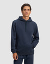 A young man with short brown hair models the Cozy Earth Men's Cityscape 2.0 Hoodie in dark blue, featuring a front pocket and hood, paired with matching pants against a light gray background.|Color:Eclipse
