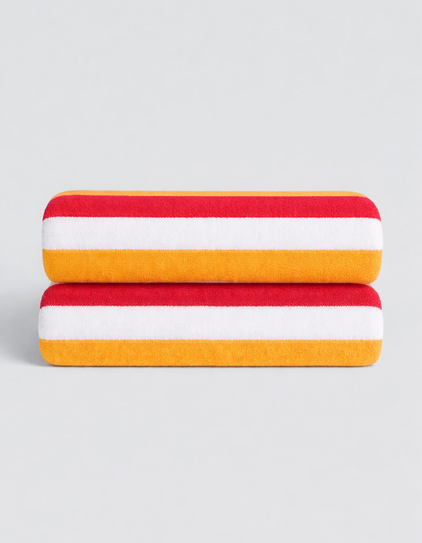 The Classic Stripe Resort Towel Bundle by Cozy Earth features two neatly folded towels with bold red, white, and yellow stripes, stacked on a simple light gray background.
