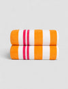 The Classic Stripe Resort Towel Bundle by Cozy Earth, in Picante Stripe, features two neatly folded towels with bold orange, white, and pink stripes stacked together against a plain light gray background.|Color:Picante Stripe