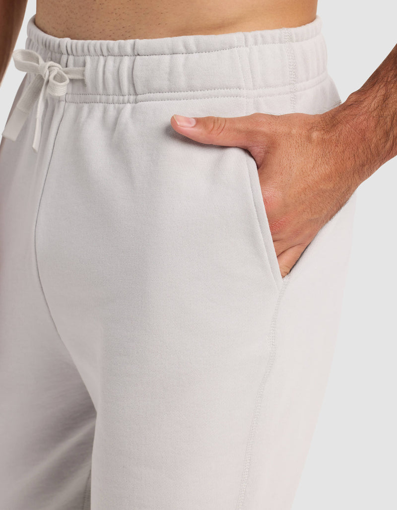 A man models the Cozy Earth Men's Dylan Jogger in light gray, with one hand in the pocket, highlighting the drawstring waistband and side seam detail.