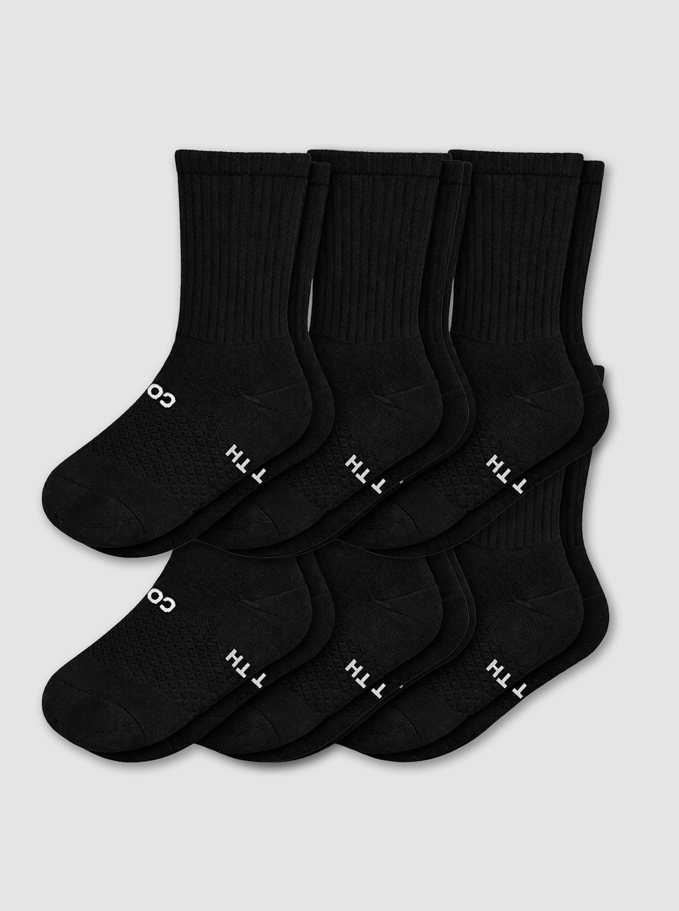 Six pairs of black Women's Essential Calf Socks by Cozy Earth are neatly overlapped with "COTTON" partially visible in white on the soles, displayed against a light gray background.|Color:Black