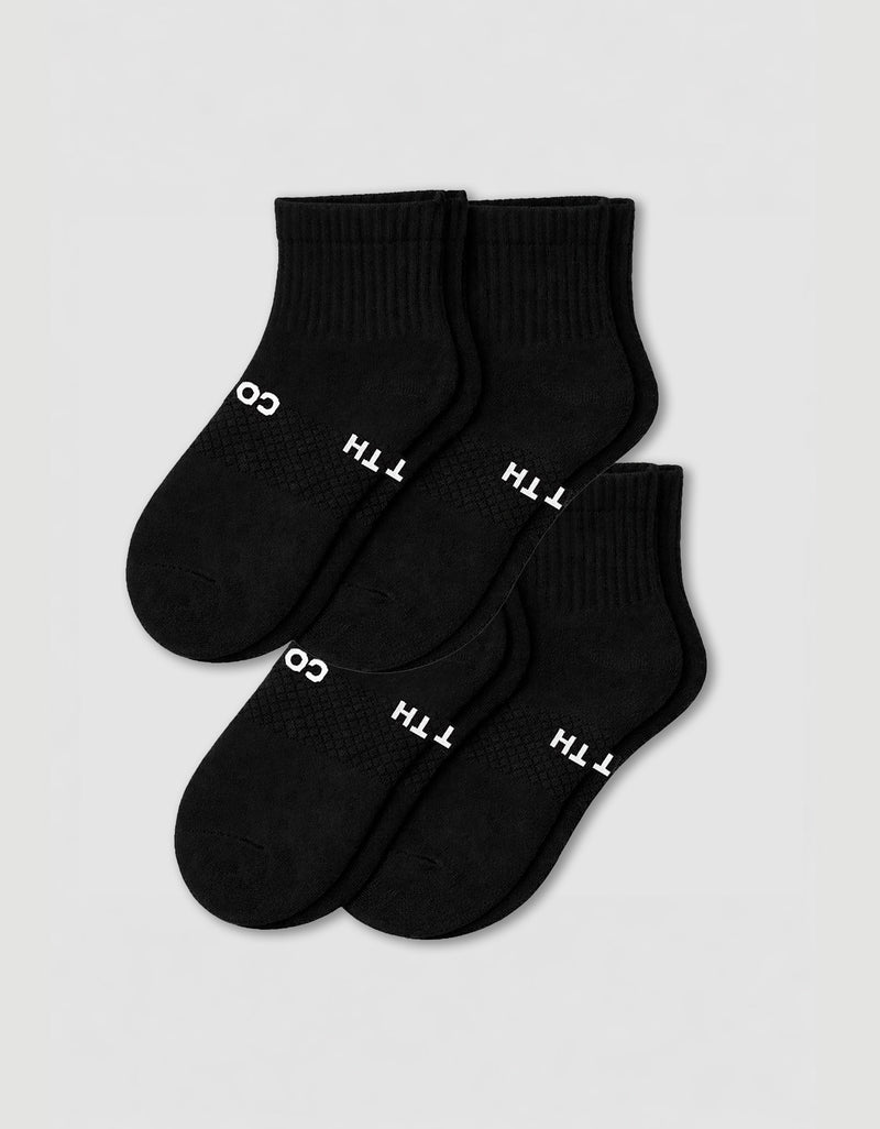 Four pairs of Cozy Earth Women's Essential Quarter Socks in black, featuring ribbed cuffs and white text, are arranged overlapping on a plain light background.