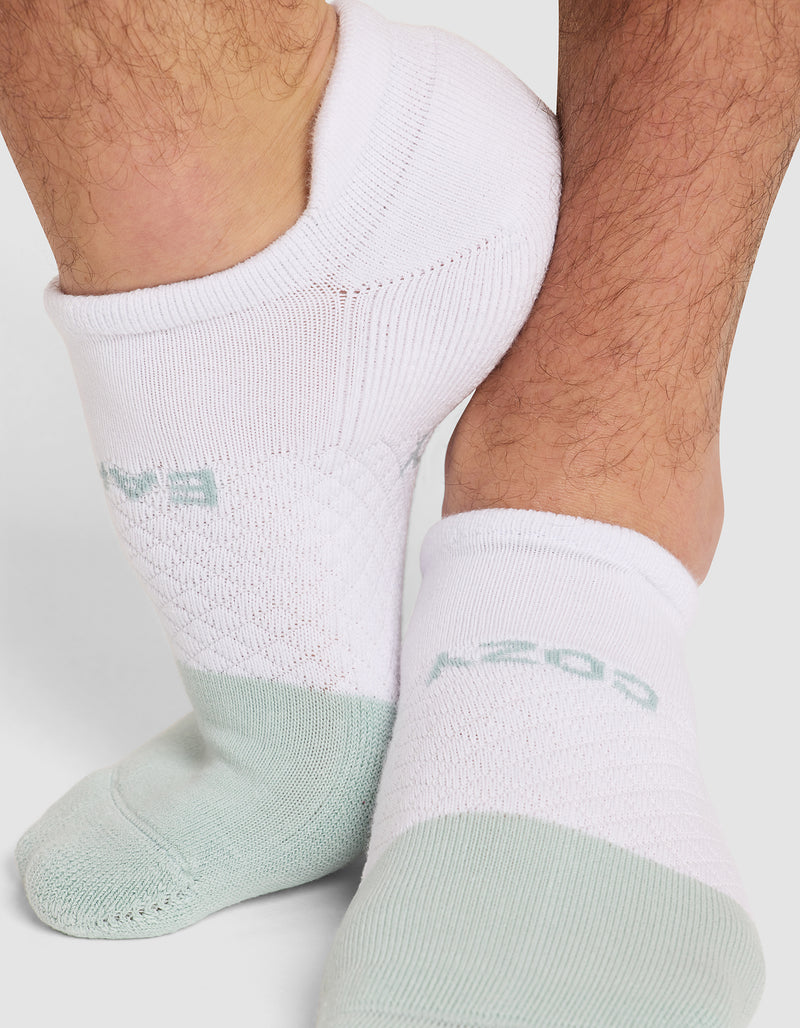 Close-up of a person wearing Cozy Earth Essential Ankle Socks in white and light green, featuring soft, textured fabric and visible leg hair.