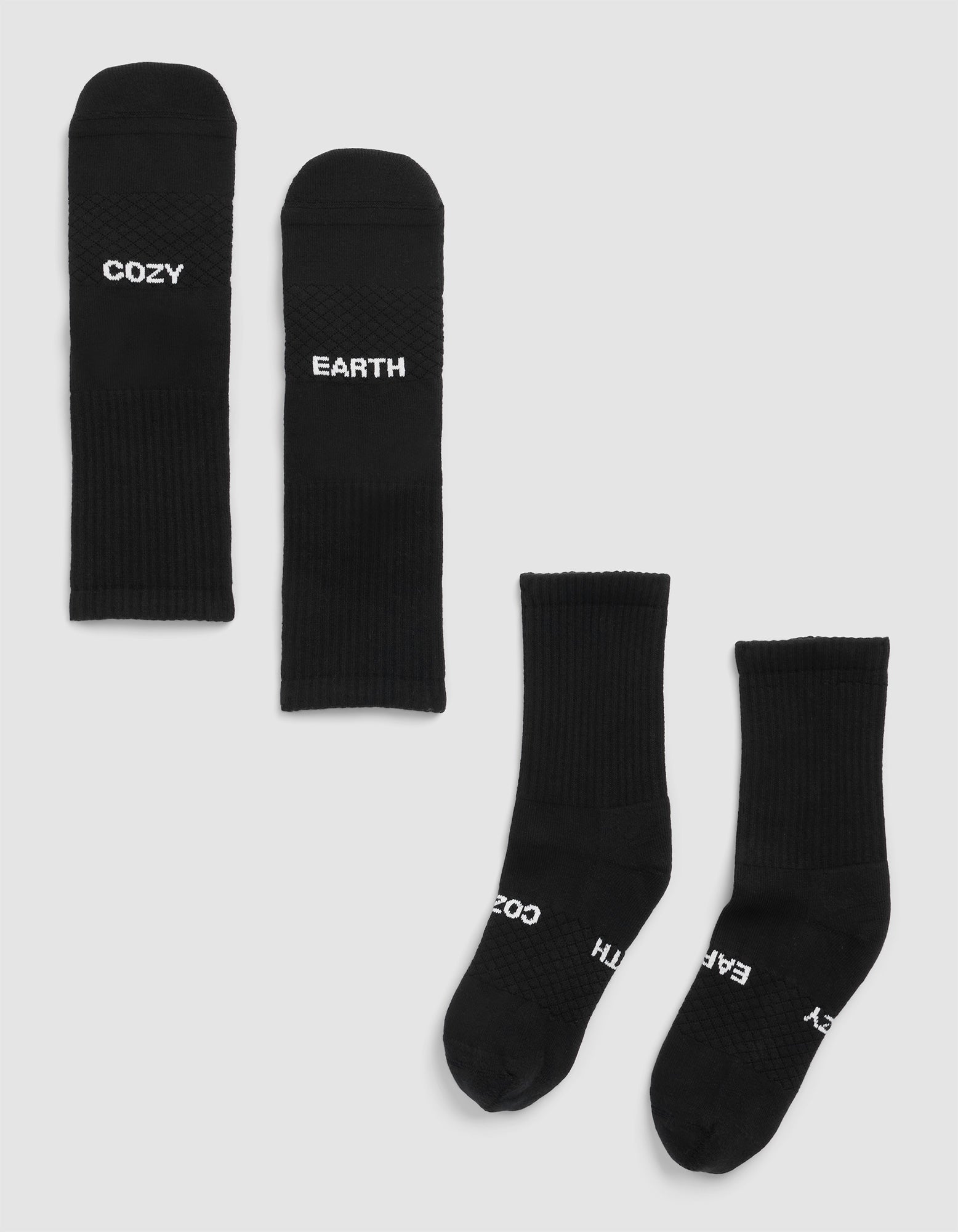 Four Essential Calf Socks by Cozy Earth in black are on a light background—two laid flat display "COZY" and "EARTH", while two others are side by side with partial text visible. 