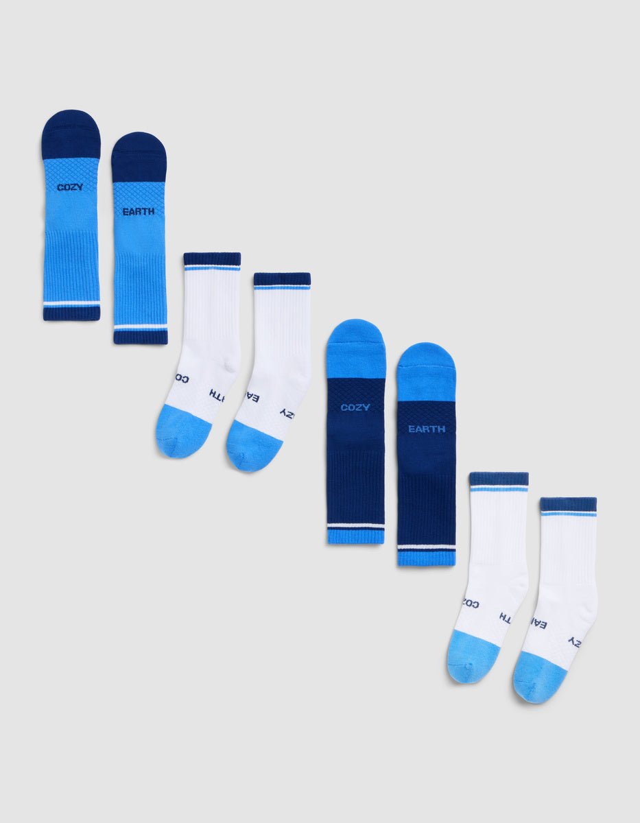 The Essential Calf Sock 4-Pack by Cozy Earth is displayed diagonally on a light gray background, featuring blue and white color-blocked designs with visible text on the sides and soles. |Color:Harbor