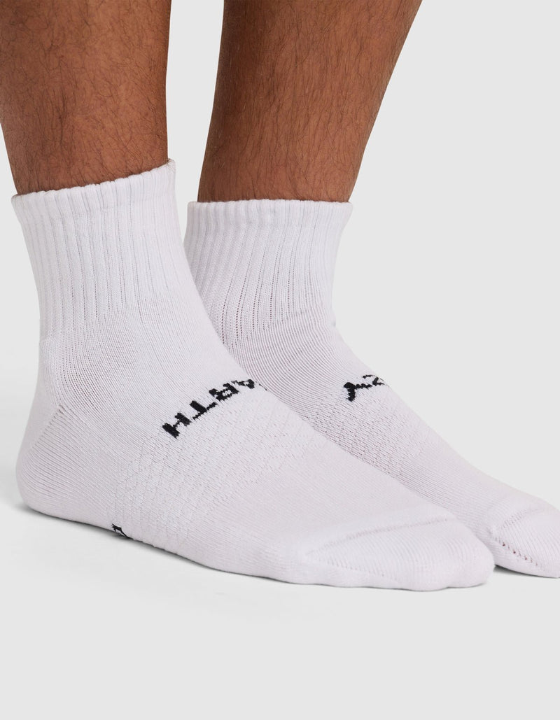 A person stands on a white background wearing Cozy Earth Essential Quarter Socks, which feature black side text, a ribbed cuff, and textured top detailing.