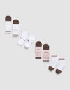 A diagonal row of six pairs of Essential Quarter Sock 4-Packs by Cozy Earth in brown, white, and pink on a light gray background. Some socks feature printed text like "COZY," "EARTH," |Color:Cedar
