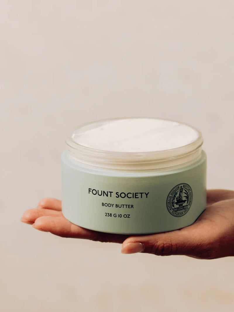 A woman holds Fount Society Body Butter jar in her hand