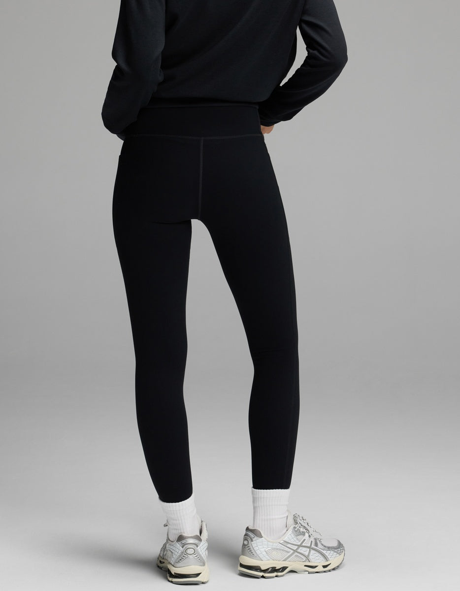 A person wearing black Women’s Liv Leggings with Pockets, white socks, and athletic shoes, viewed from behind.