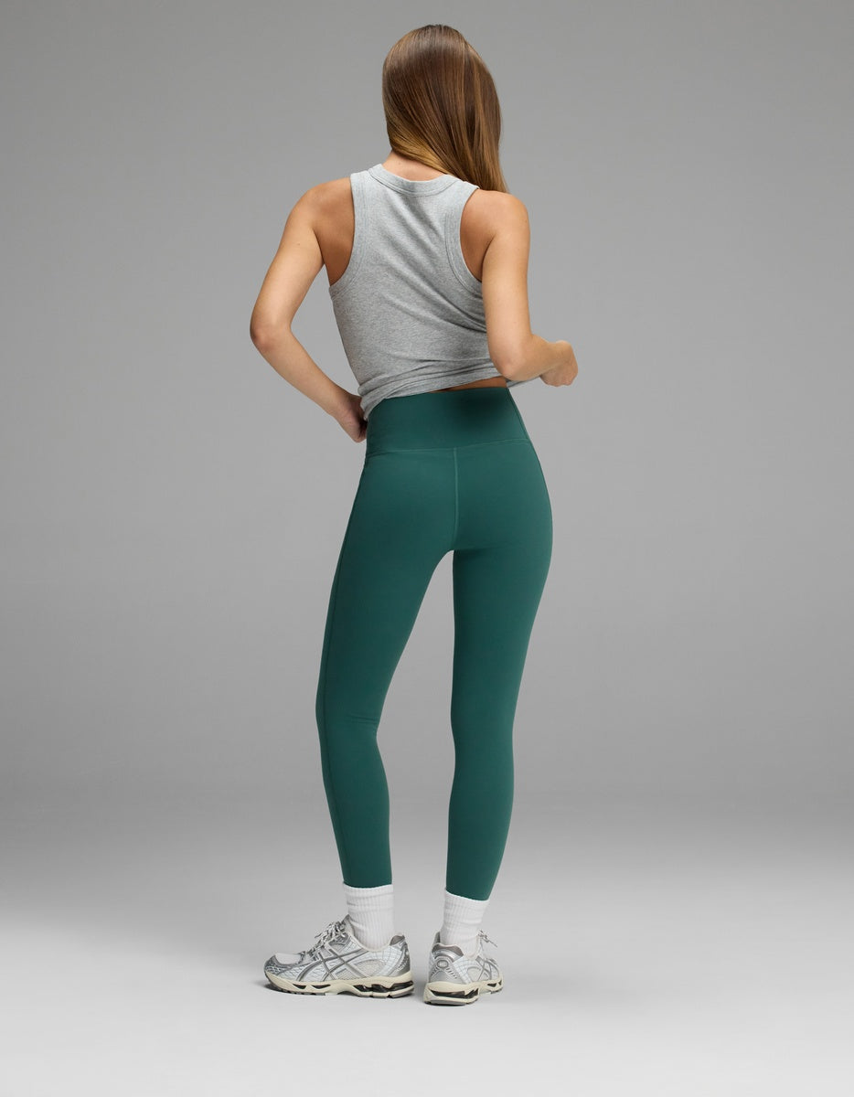 A person viewed from behind wearing a gray tank top and forest green Women’s Liv Leggings with Pockets.