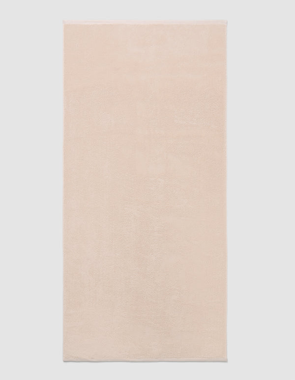 The Cozy Earth Loop Terry Bath Mat, a rectangular bath mat in light beige with a soft, plush texture, is displayed against a plain white background.|Color:Petal