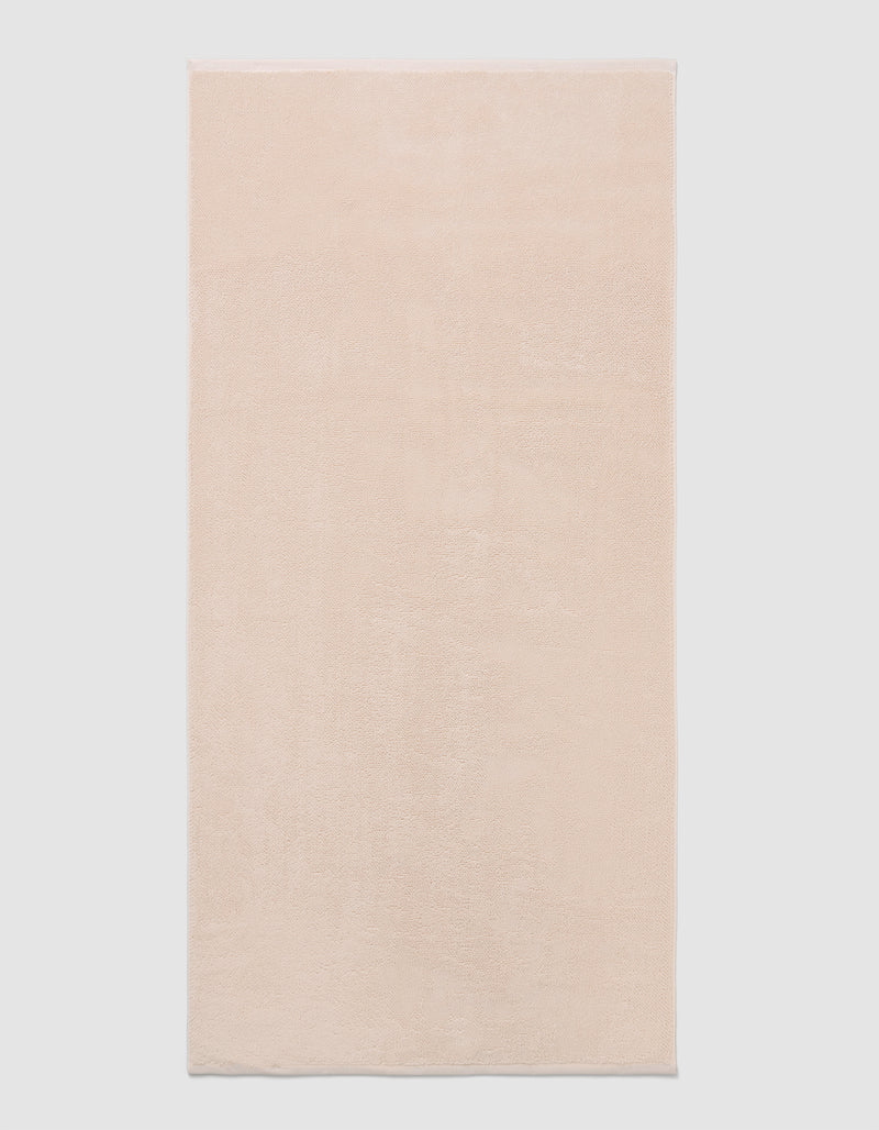 The Cozy Earth Loop Terry Bath Mat, a rectangular bath mat in light beige with a soft, plush texture, is displayed against a plain white background.