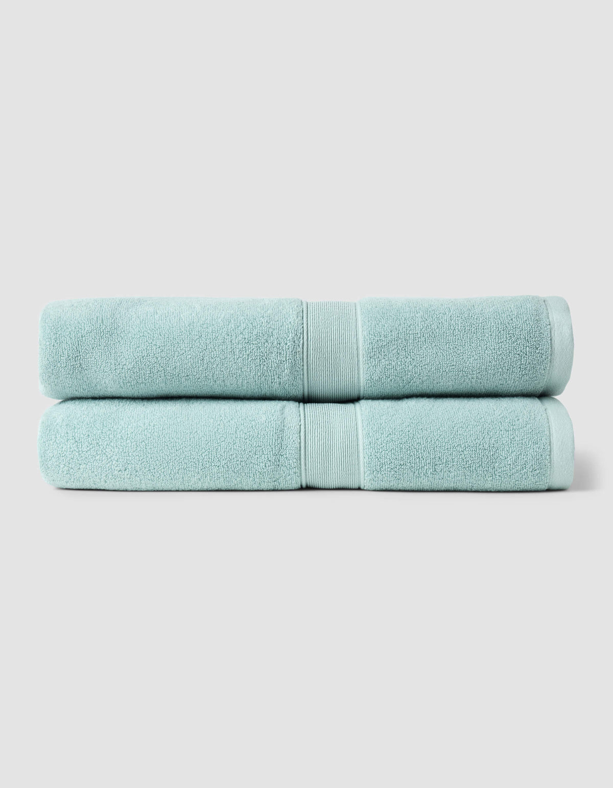 Two Luxe Bath Sheets by Cozy Earth, neatly folded and stacked, feature a light blue color against a plain, light gray background.|Color:Tide