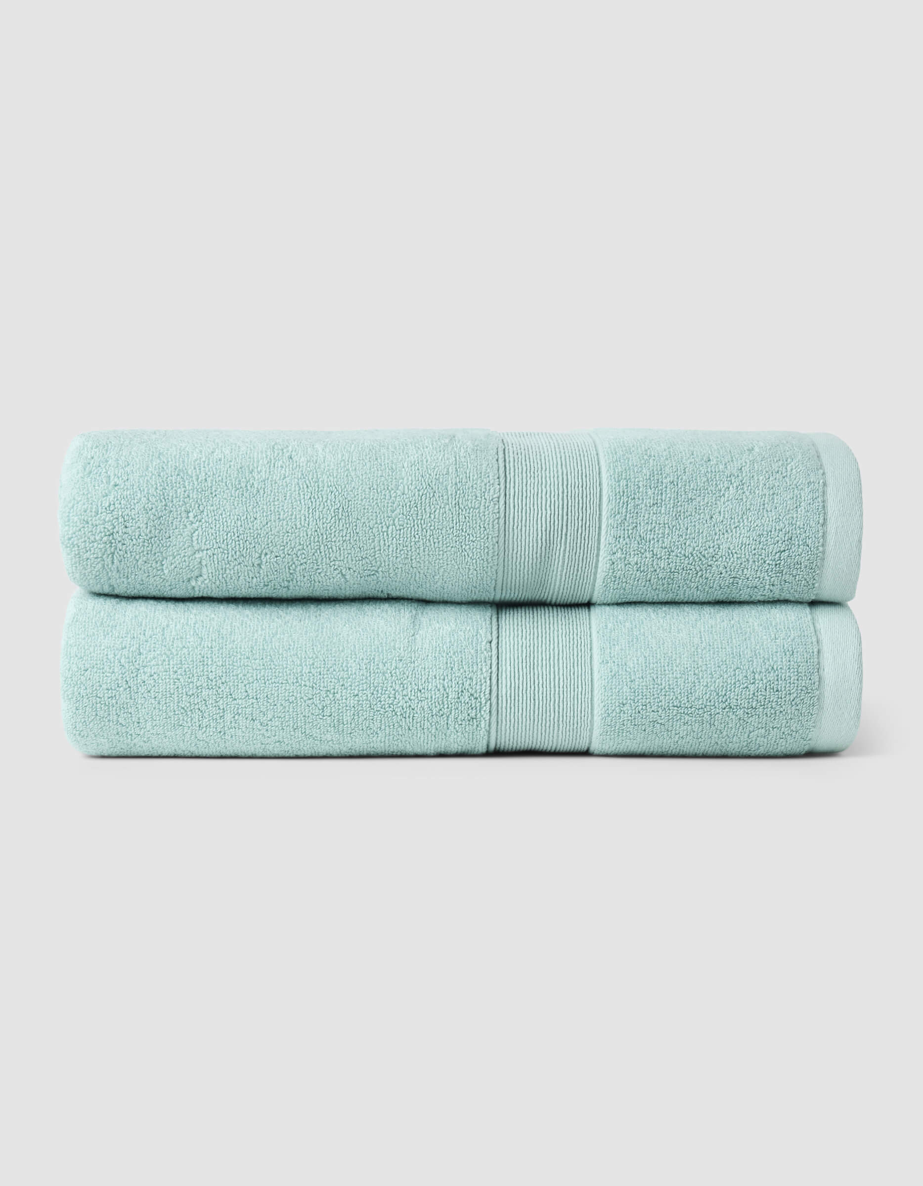 Two Luxe Bath Towels from Cozy Earth, neatly folded and stacked, displayed against a plain light gray background.