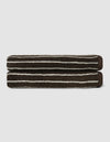 The Complete Striped Luxe Bath Bundle by Cozy Earth features two dark brown towels with thin, irregular white stripes, neatly rolled and stacked on a light gray background.|Color:Espresso Coconut Stripe