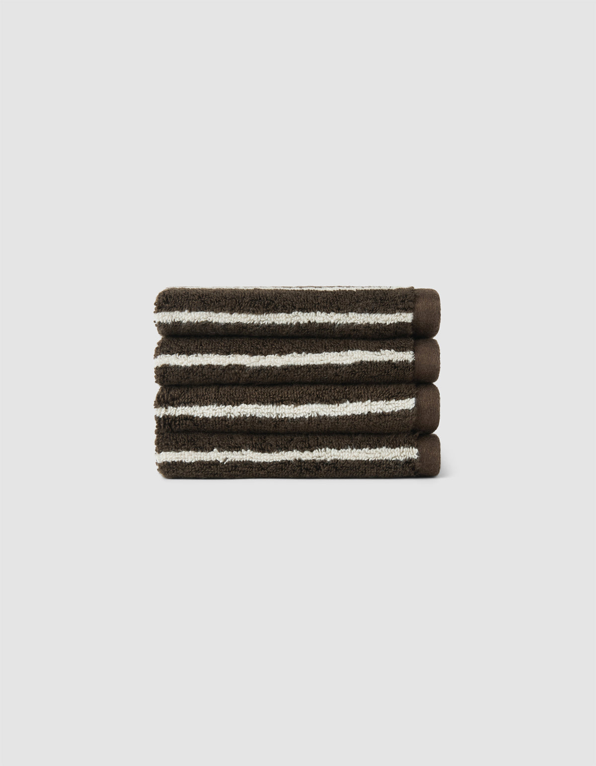 The Cozy Earth Striped Luxe Bath Towel Set features three neatly folded dark brown towels with white stripes, stacked on a light gray background.|Color:Espresso Coconut Stripe