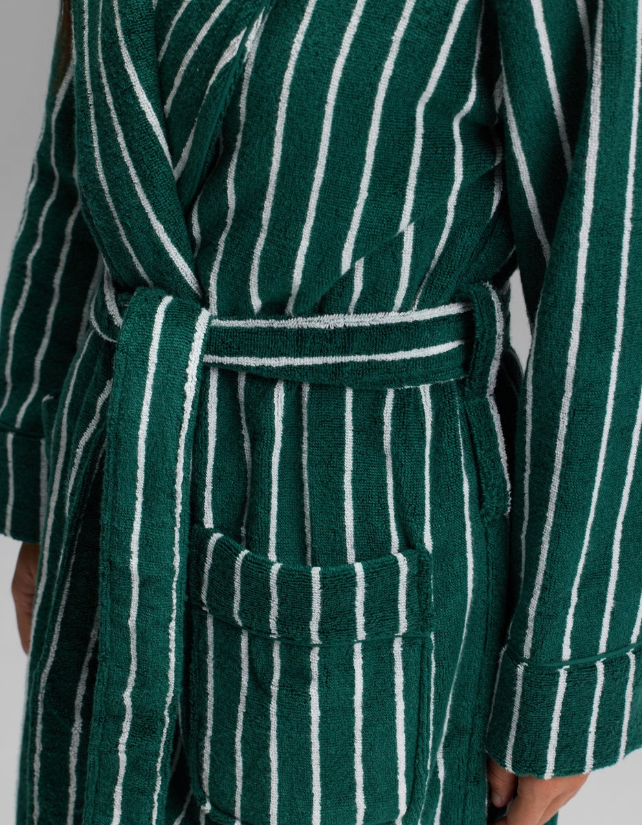 Close-up of a person wearing the Cozy Earth Luxe Bath Robe in dark green with white vertical stripes, featuring a belted waist and a front pocket.