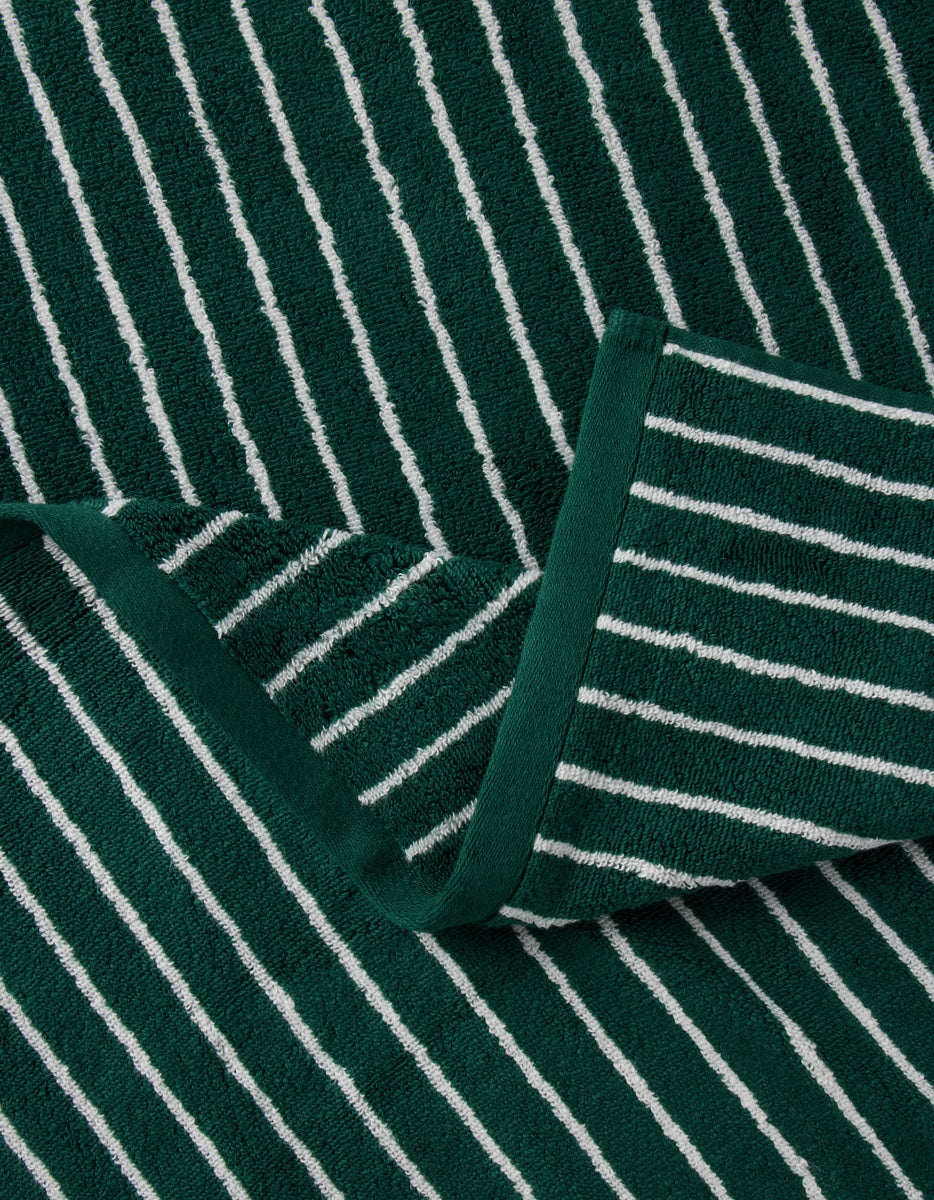 A Luxe Bath Sheets by Cozy Earth is neatly folded, displaying its green color with white vertical stripes and soft textured fabric.