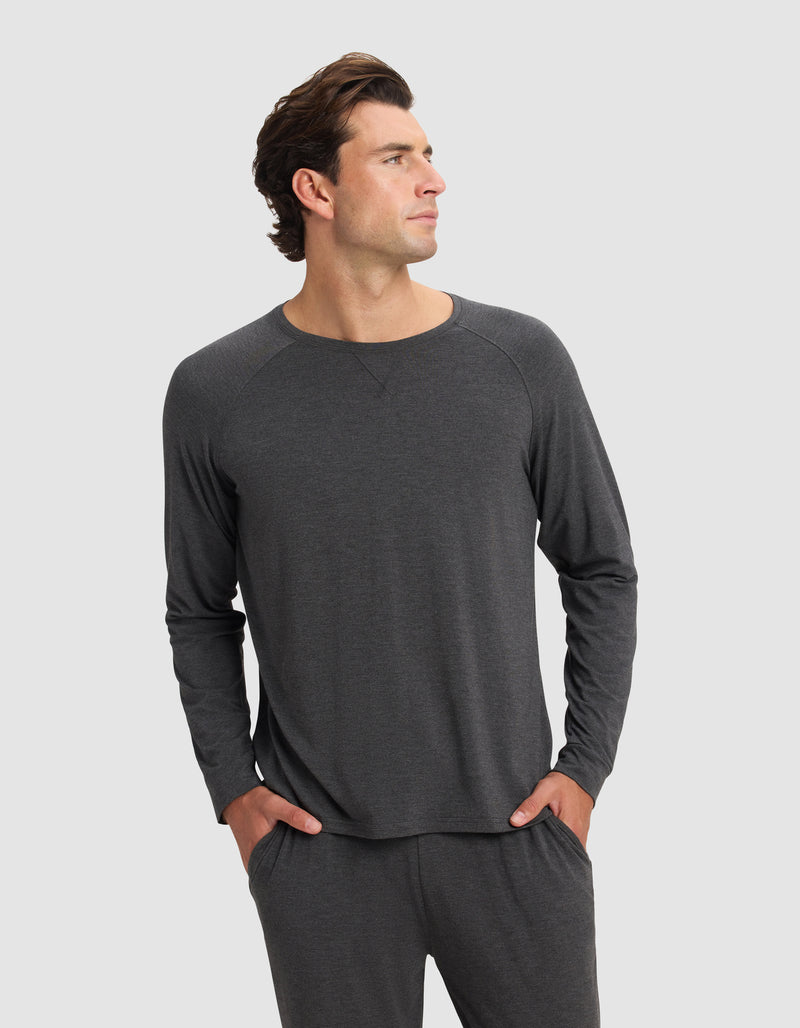A man wearing the Cozy Earth Men's Bamboo Stretch-Knit Long Sleeve in dark gray stands with his hands in his pockets, looking to his left, against a plain light background.