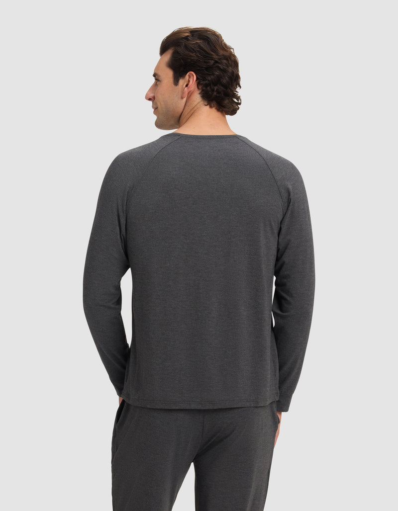 A man with dark hair stands facing away from the camera, wearing the Cozy Earth Men's Bamboo Stretch-Knit Long Sleeve in dark gray, paired with matching pants, set against a plain light background.