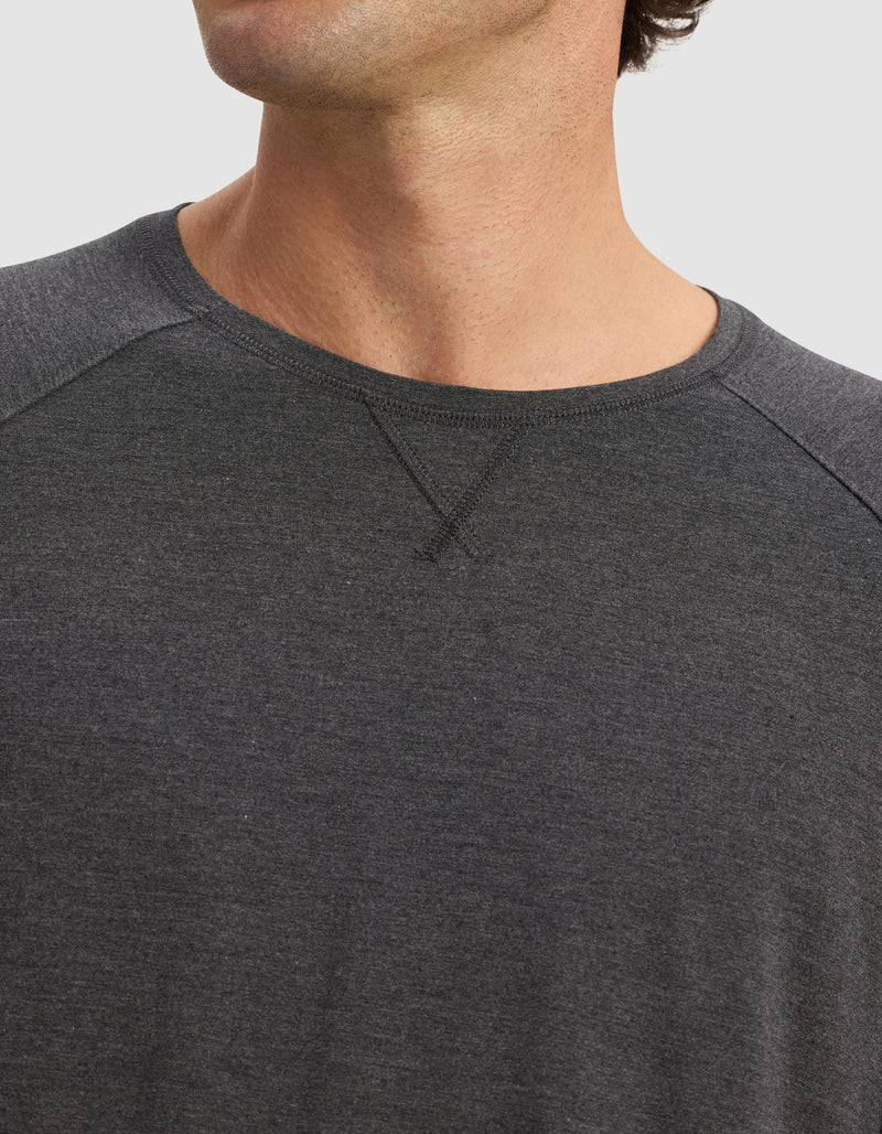 Close-up of a person wearing the Cozy Earth Men's Bamboo Stretch-Knit Long Sleeve in dark gray with raglan sleeves. The face is partially hidden, and the background is plain white.