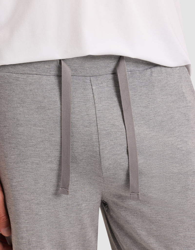 Close-up of a person wearing Cozy Earth Men's Bamboo Stretch-Knit Pajama Shorts in light gray with a drawstring waist, paired with a partially visible white shirt.
