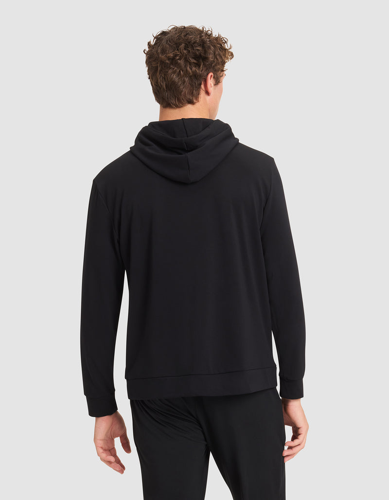 A man with curly hair is seen from behind wearing a Cozy Earth Men's Brushed Bamboo Hoodie in black, paired with black pants, set against a plain light gray background.